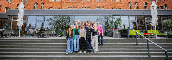 Gruppenfoto des youpan auf einer Treppe vor einer Glasfront eines Gebäudes